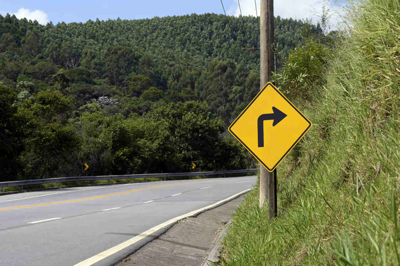 Uma placa de advertência indicando que existe uma curva à direita.